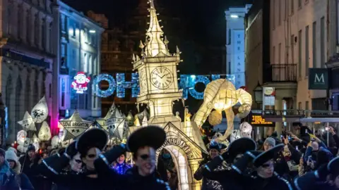 Getty Images A large crowd of people carrying lit-up lanterns. 