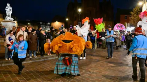 Stuart Walker A cuddly haggis in a kilt leads the Big Burns Supper parade through Dumfries with a statue of Robert Burns in the background