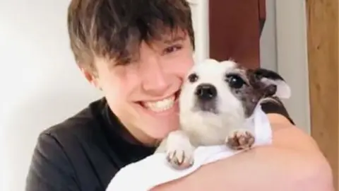 Family handout Barney smiling in black top holding a dog 