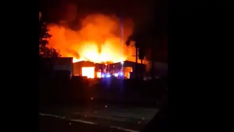 A large fire at a building is seen at night time.