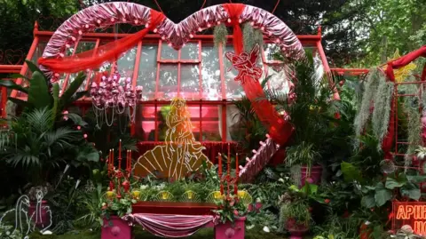 Malvern Garden Buildings A garden with a a range of plants and large pink love heart and red ribbons