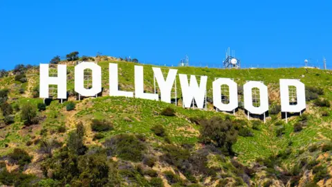 A view of Hollywood sign, shot from below shown against a blue sky and green hills