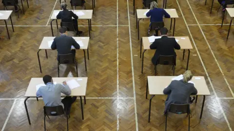An aerial image, captured from behind, of secondary pupils taking their exams while seated at individual desks