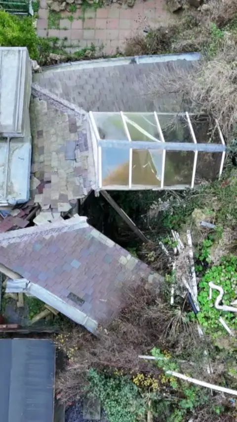 An aerial view of a landslip, with a collapsed roof.