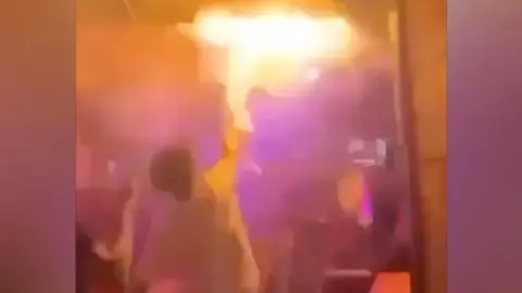 Person tries to put out flames inside Swiss bar
