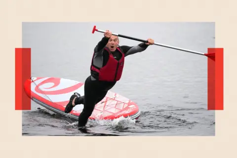 Christopher Furlong/Getty Images Liberal Democrats Leader Ed Davey enjoys some paddle boarding on Lake Windermere during a campaign visit