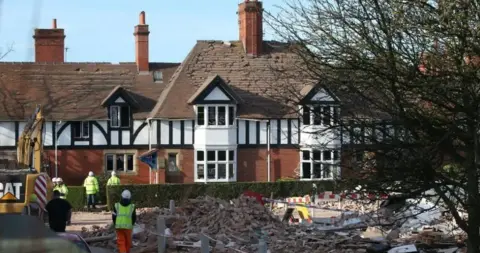 PA Media Image shows a 1920s house with many of its roof tiles knocked out of place by the force of the explosion, and the debris of a destroyed building in the foreground