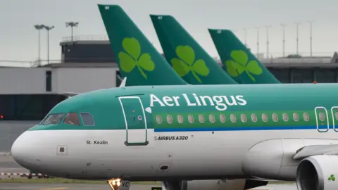 Getty Images 绿白相间的飞机，上面写着爱尔兰航空的字样，背景中有三架飞机尾翼，每架飞机尾翼上都有爱尔兰航空的三叶草标志