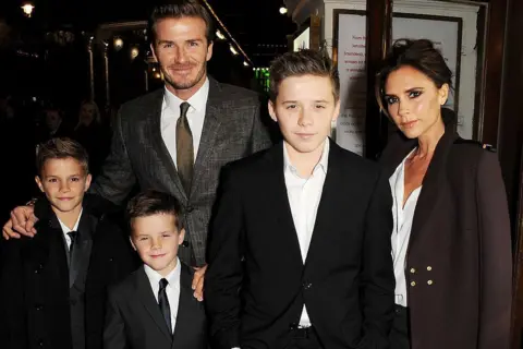 Getty Images Brooklyn (front centre) dressed in a blazer as a young teen, posing with his family at a gala performance of Spice Girls musical Viva Forever 