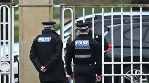 Getty Images Police officers at the gates of Royal Lodge, Andrew Mountbatten-Windsor's former residence in Windsor Great Park