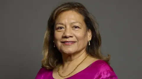 House of Commons/Roger Harris A portrait of Valerie Vaz. She has shoulder length brown hair and is wearing a dark pink top with a gold necklace