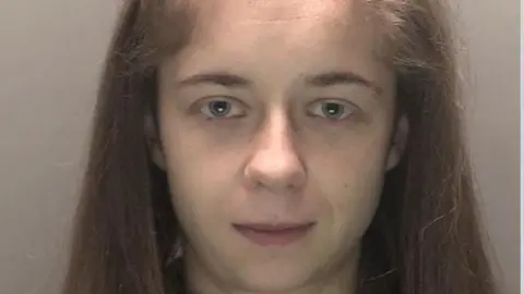 Emma McAteer custody shot: a woman with long, brown hair and blue eyes