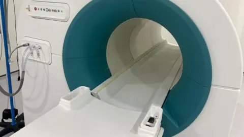University of Aberdeen The fast field cycling imaging scanner's patient bed which is white with a blue/green circle surrounding the entry to the white scanner