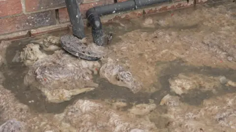 Watery sewage against the backdrop of a brick wall
