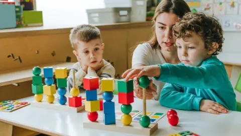 Children play with blocks at a classroom desk