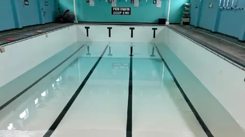 Newcastle Emlyn Swimming Pool Newcastle Emlyn Swimming Pool. It is an indoor pool surrounded by walls painted in different shades of blue. The pool is half filled in the photograph.