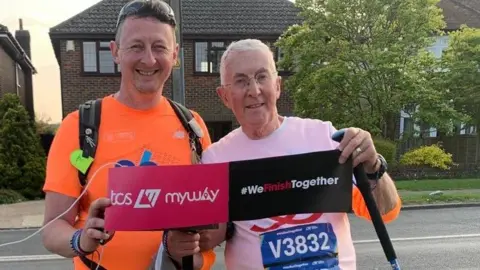 David Walker and his son complete the virtual marathon, holding a sign saying we finish together