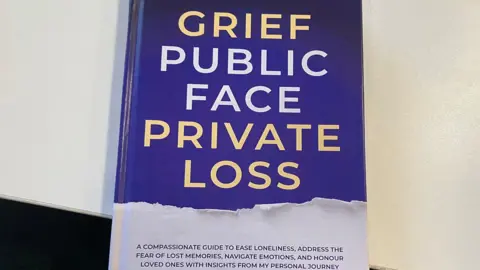 Toby Friedner/BBC A navy book with gold and white font displaying the title: "Grief, Public Face, Private Loss"