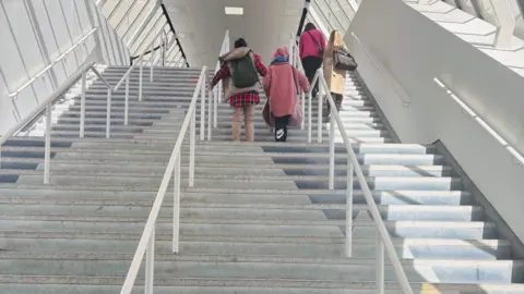 Thirty-two steps leading up to a shopping centre, four people are on the stairs.
