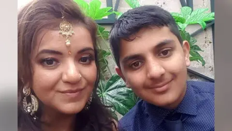 Family handout Pooja Kanda, wearing traditional gold jewellery and a bindi, with Ronan wearing a smart blue shirt and tie 