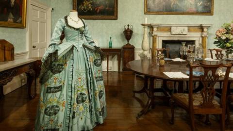 A 18th century style ballgown in duck egg blue with a duck egg blue with floral brocade and ruffled cuffs. 