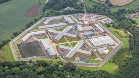 Aerial shot of Lowdham Grange prison - a series of modern buildings set in countryside