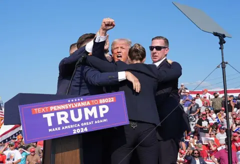 Photo by Jabin Botsford/The Washington Post Former US President Donald Trump is swarmed by secret service on stage at a rally in Butler, PA 