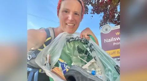 Gill Thomas pictured holding a bag full of rubbish. She is looking at the camera and smiling. 