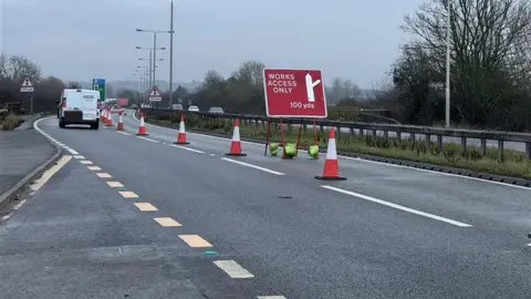 The A52 is pictured. It is a dual carriageway road with one lane closed off with orange traffic cones