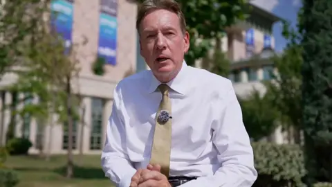 Frank Gardner in a white shirt and yellow tie