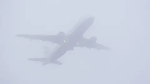 A plane takes off in misty conditions from London Gatwick airport in Crawley, West Sussex.