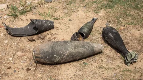 Five pieces of black shrapnel lie on a dusty ground