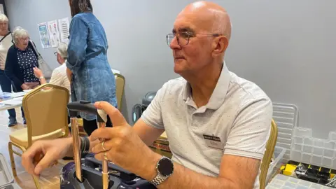 Jo Liversidge John repairs a suitcase, he's concentrating hard