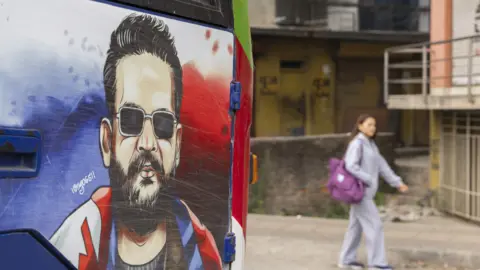 A person walks past a bus displaying a sticker of Balen Shah in Kathmandu