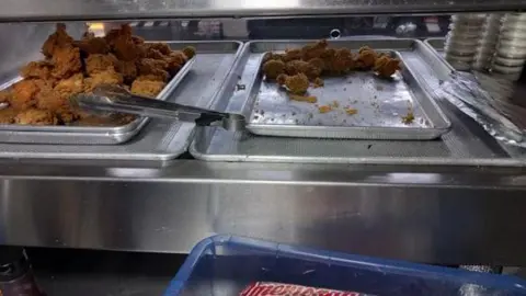 Stockport Council Fried chicken on metal trays in kitchen. No light heating the cooked chicken which is sat on the side.