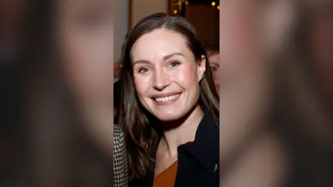 A woman smiling, with long dark hair.