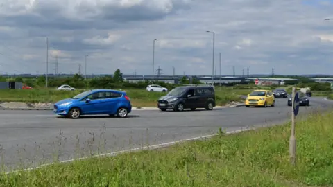 Google Cars driving around a large roundabout.