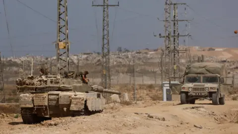 Reuters Israeli military vehicles patrol the Israeli side of the border with Gaza (27 May 2025)