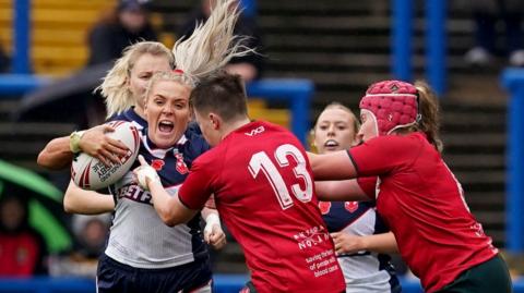 England's Amy Hardcastle (left) holds of tackled from Wales' Shaunni Davies (centre) and Wales' Sara Jones (right