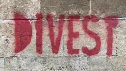 Supplied Red pain, on a university building wall, spells out the word 'Divert'. 