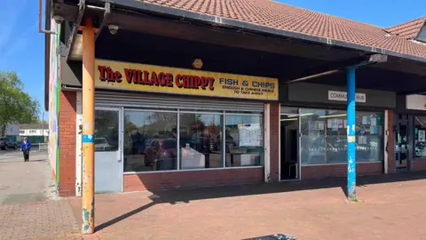 Fish and Chip shop. The sign above the shop reads 'The Village Chippy'.