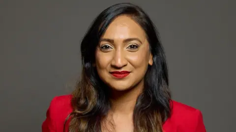 Southampton Test MP Satvir Kaur smiling for the camera. She is wearing a red outfit.