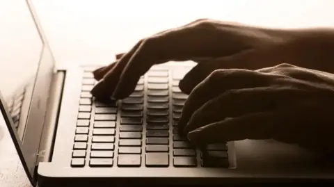 A close-up of someone's hands hovering over a laptop keyboard. 