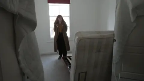 Freazy stands in a room around upturned furniture 