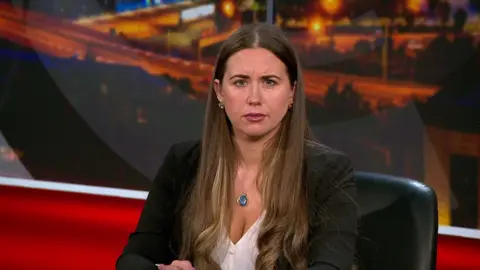 Sorcha Eastwood, a woman with long dark hair, in a black blazer with a white blouse, sat in the View studio