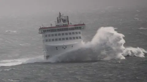The Manxman ferry in rough seas with a large wave breaking at the front.
