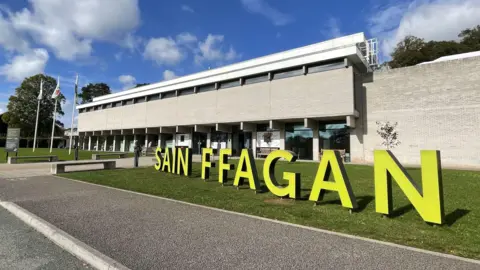 The exterior of museum with large yellow letters individually standing which spell out 'Sain FFAGAN'.