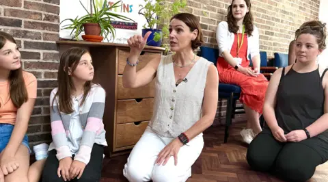 Martin Giles/BBC Suranne Jones and unnamed children and teenagers at her drama workshop