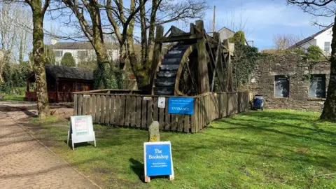A bookshop on a green with signs outside.