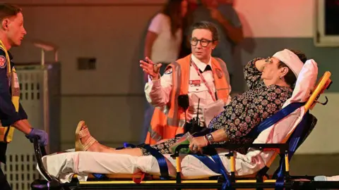 Getty A woman with a bandage around her head is transported on a stretcher.